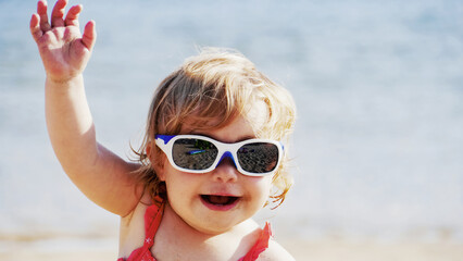 A baby waving at the beach/Un bébé faisant coucou à la plage