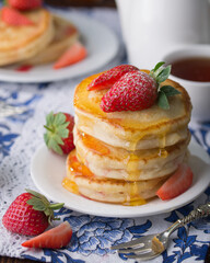 Stack of pancakes with strawberries and honey