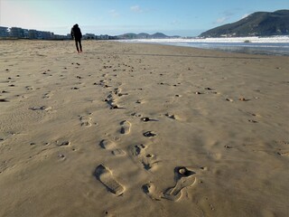 A man leaves his footprints on the sand of the beach.

