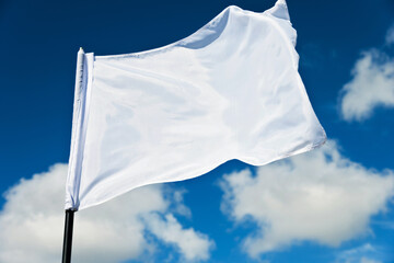 White flag flying against blue sky - obrazy, fototapety, plakaty