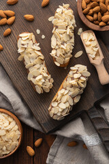 Eclairs with almond petals on a wooden board