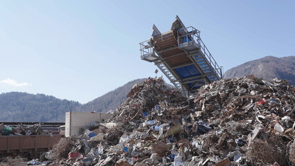 Crushed recycling steel pieces falling from conveyor belt to big pile