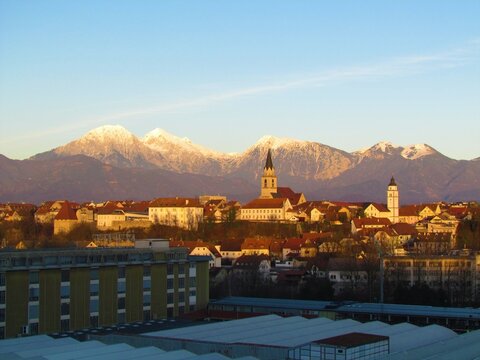 Scenic cityscape of the town of Kranj the capital of Gorenjska region of Slovenia with the church of st. Kancijan and the ruins of Kieselstein castle lit by sunlight with the peaks of Grintovec