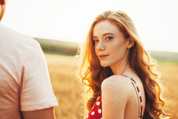 Guy and girl with red hair standing on among dry fields on an autumn dunny day. Closeup portrait. Beauty face.