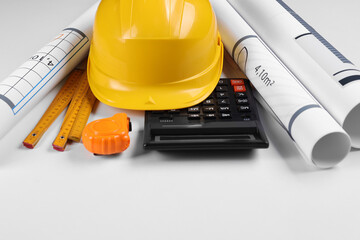 Construction drawings, safety hat, calculator, tape measure and folding ruler on white background