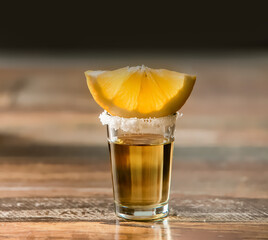 tequila shot drink in a glass decorated with salt with slice of fresh lemon, splash of the drink, frozen movement, pub or night life