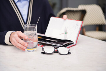 A man drinks a glass of water and reads a book