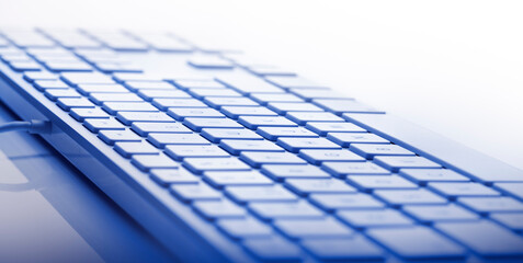 Shallow depth of focus on keyboard against white background. Focus on center of keypath. Blue color banner