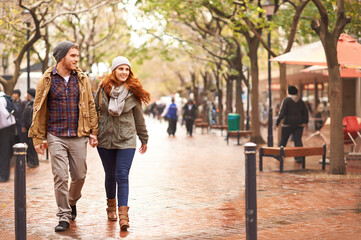 Taking a walk on the winter side. Shot of a happy young couple walking through an urban area...