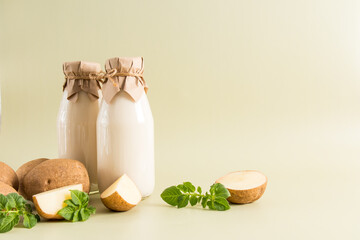 vegan vegetable milk from potato tubers in two glass bottles on a pastel background with a copy of...