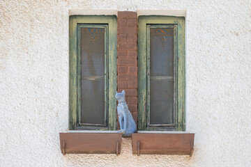 Fototapeta na wymiar blue sculpture of sitting cat at the window in Zikhron Ya'akov, Israel