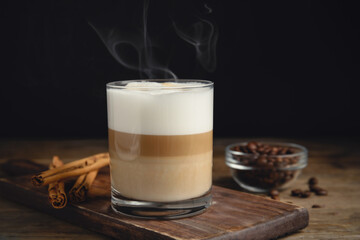 Delicious latte macchiato, cinnamon sticks and coffee beans on wooden table - obrazy, fototapety, plakaty