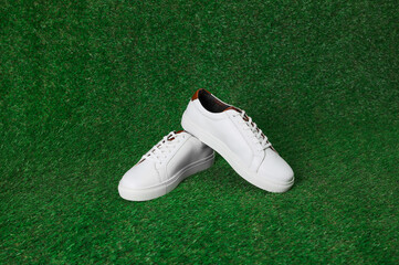 Pair of stylish sports shoes on green grass