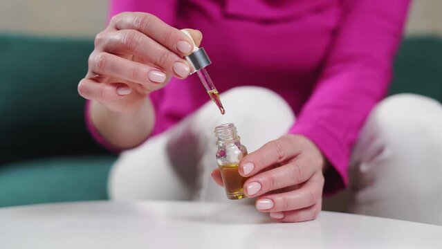 Close up woman hands with glass droplet bottle of essential oils. Wellness natural remedies.