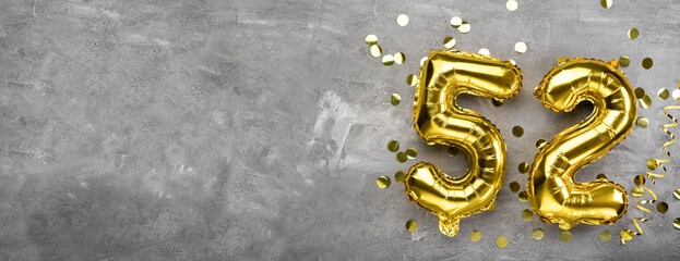 Yellow foil balloon number, number fifty two concrete background. Greeting card with the...