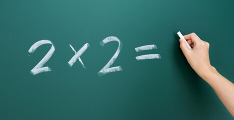 Hand writing math simple equation on blackboard