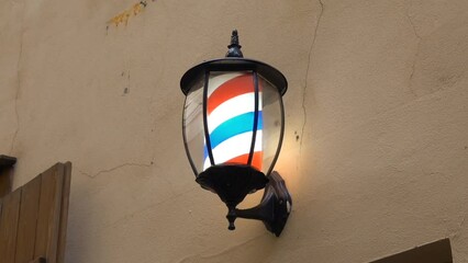 Vintage illuminated barber shop sign with rotating white, blue and red stripes on street in Prague. High quality FullHD footage