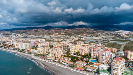 Obraz premium Drone perspective of costal city of Torrox situated in Malaga, Costa del Sol, Spain. Touristic travel destination. View of the promenade and beach area. The lighthouse of Torrox and the river.