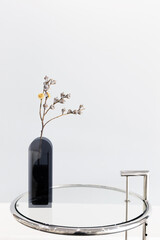 Dried flower in modern design vase on glass table. Minimal decoration in cafe or house minimalism interior design. 