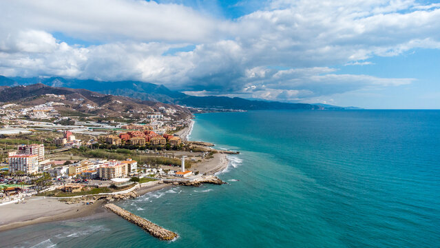 Drone perspective of costal city of Torrox situated in Malaga, Costa del Sol, Spain. Touristic travel destination. View of the promenade and beach area. The lighthouse of Torrox and the river.