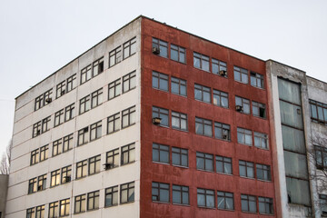 Front facade of an old abandoned white red building. Corner of a house, business, factory, commercial, retail, office space. Architecture of a post-Soviet Union. Straight geometric shapes of buildings