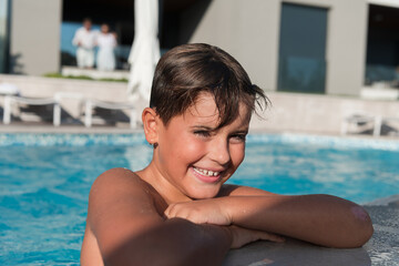 The boy enjoys a summer day swimming in the pool. The concept of a family vacation. Selective focus 