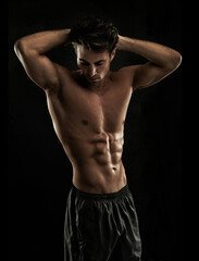 Fototapeta na wymiar Chiseled abs. Muscular young man showing off his defined body.