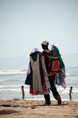Hombre de raza negra vendiendo ropa por la playa.