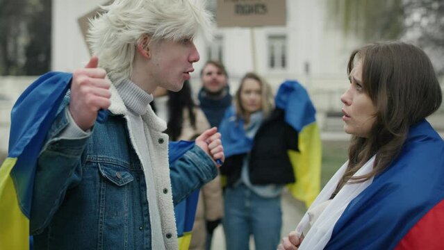 Caucasian woman with Russian flag arguing with caucasian man with Ukrainian flag on street manifestation. Shot with RED helium camera in 8K. 