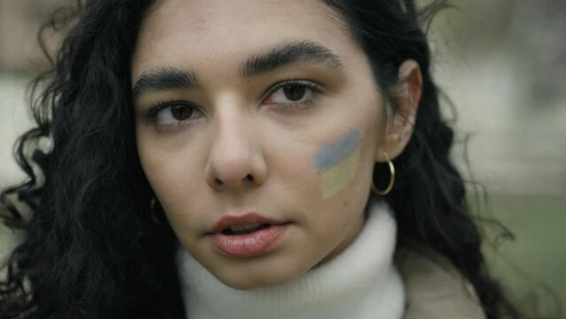Close up portrait of young woman with Ukrainian flag painted on her cheek. Shot with RED helium camera in 8K.   