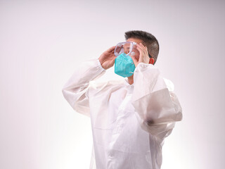 A health care worker wearing a mask and protective clothing on a solid color background
