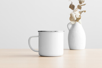 Enamel mug mockup with an eucalyptus decoration on the wooden table.