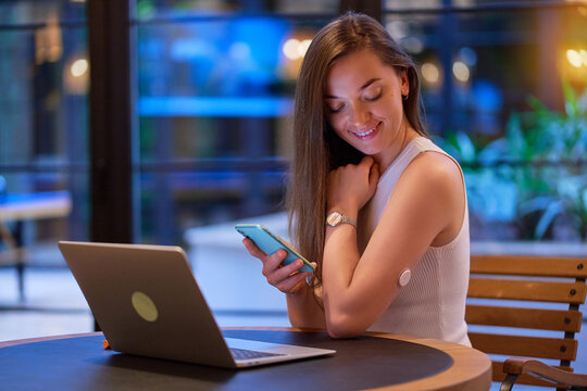 Modern diabetic patient control, monitoring and checking glucose level with remote sensor without blood during online working at cafe. Smart medical technology in diabetes treatment