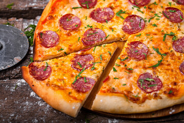 pizza with salami barbecue sausages ham tomatoes bell peppers on a wooden board sprinkled with flour