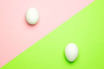 White eggs on a green and pink background. Easter concept.