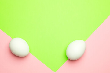Single white egg on crossing point of green and pink backgrounds. Happy Easter concept. Minimal concept.