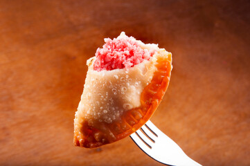 sausage pastry in closeup skewered on fork with blurred background.