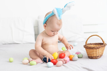 Portrait of a cute baby dressed in Easter bunny ears with a basket full of eggs