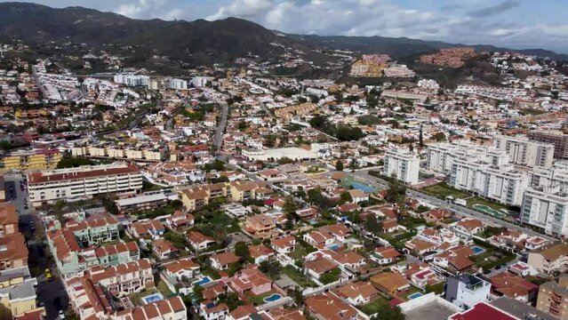 The city of Rincon de la Victoria on the coastline in the Malaga province. A town with a long beach east of Malaga. Many buildings in the city. Cloudy sky over the mountains in the background.