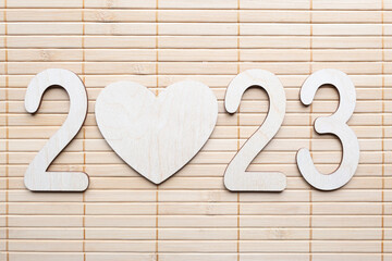 New Year 2023. Bamboo background. Flat lay. Top view. Empty wooden heart. New year concept.