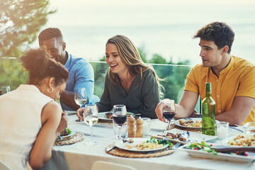 We always have the best times together. Shot of a group of friends enjoying a meal and drinks together around a table at a gathering outdoors.
