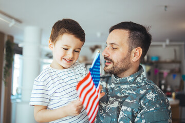 Little boy meeting his military father at home. Memorial Day celebration. An emotional military father, dressed in camouflage, holds his young son in arms in greeting after returning home..