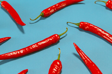 Creative composition made of red chilli pepper on blue background. Selective focus. Healthy food...