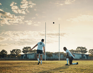 That was a master kick. Full length shot of two young rugby players training together on the field during the day.