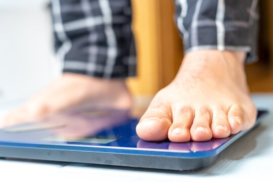 Close up of a mature man's feet on an electronic weight scale. Weight control concept. High quality photo