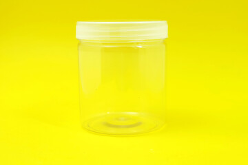 Empty transparent plastic jar on yellow background