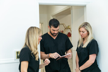 A male physician doctor at a medical spa and wellness clinic speaking to two female nurse practitioners