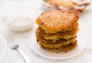 Potato pancakes with sour cream on white plate