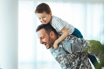 Happy reunion of one young soldier with family, five years old son and father having fun in the...