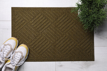 New clean door mat, shoes and houseplant on floor, flat lay